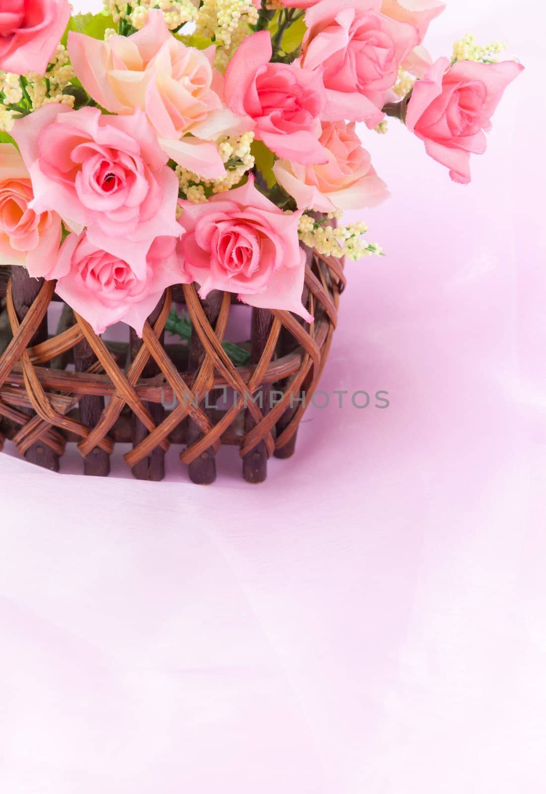 Roses in wood basket on fabric pink background