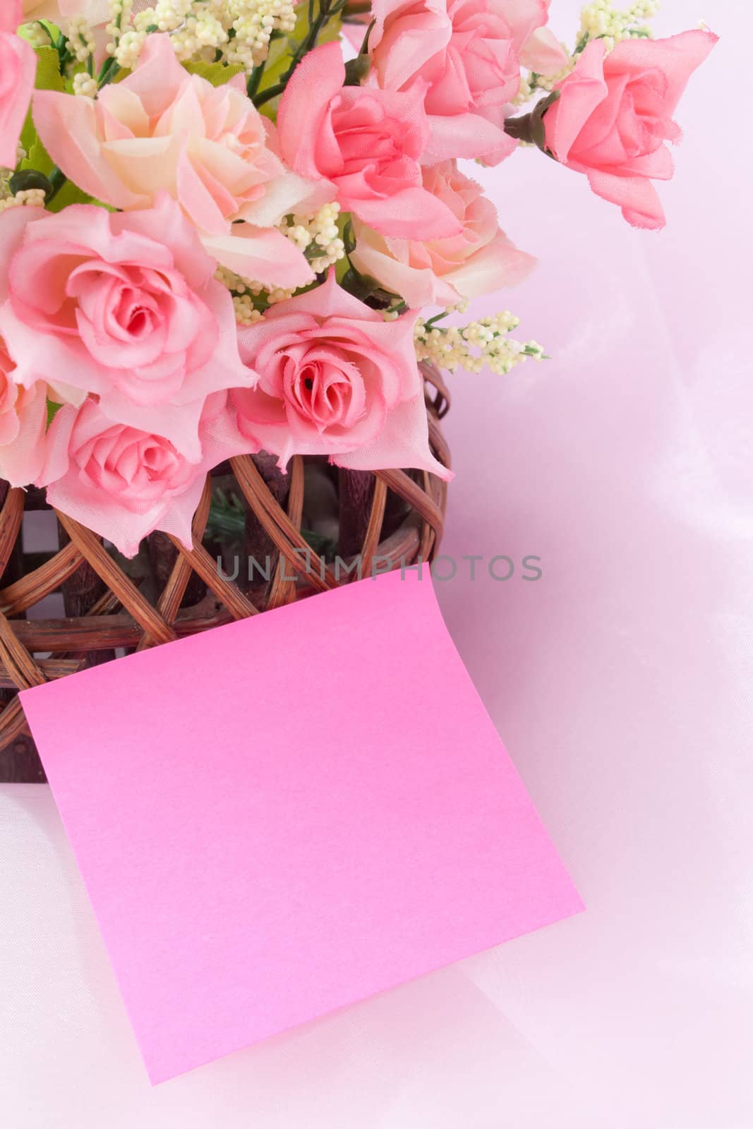 Roses in wood basket on fabric pink background