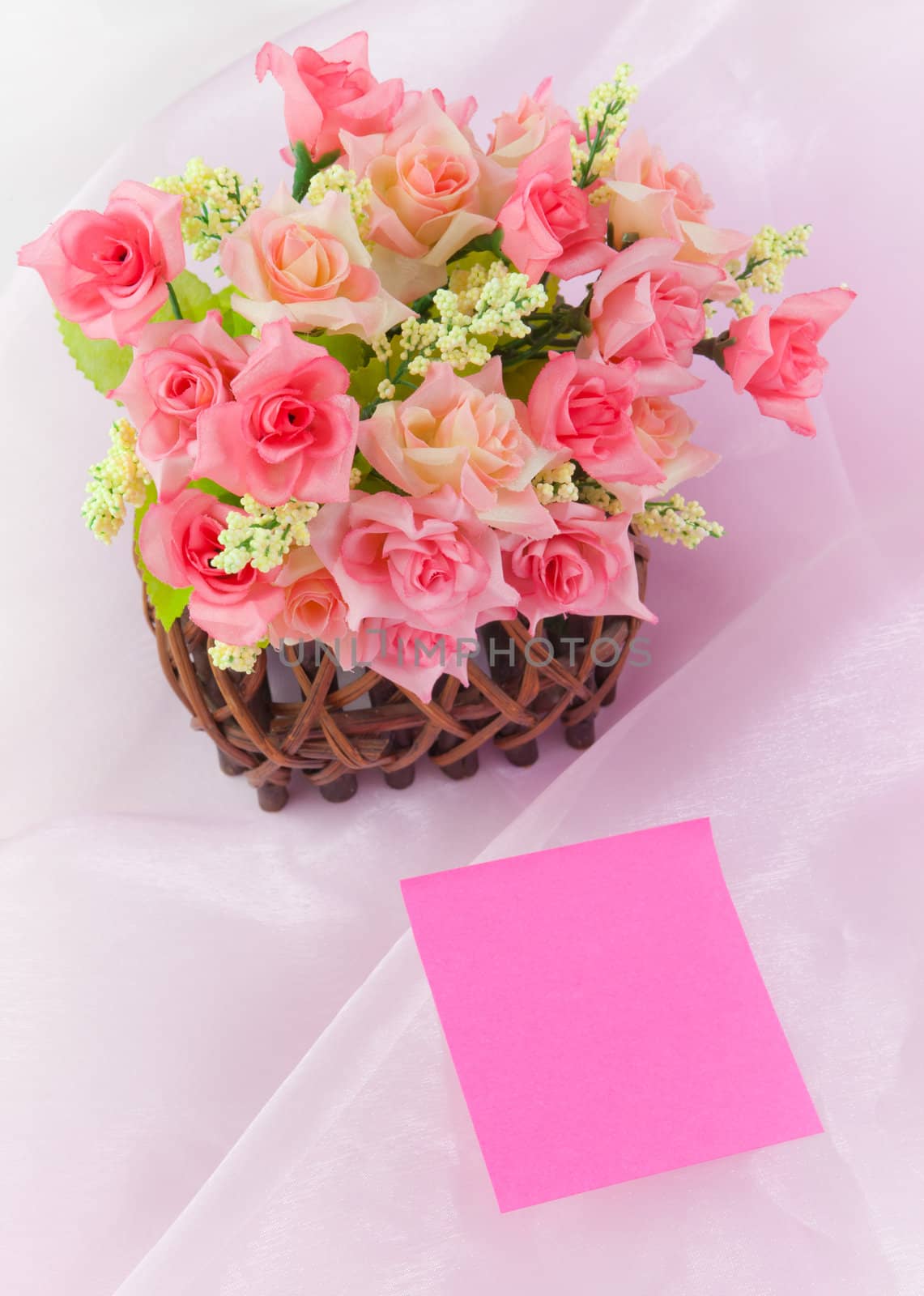 Roses in wood basket on fabric pink background