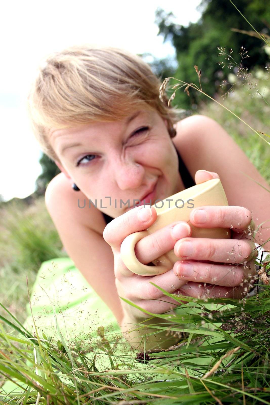 girls is drinking from a cup on a meadow