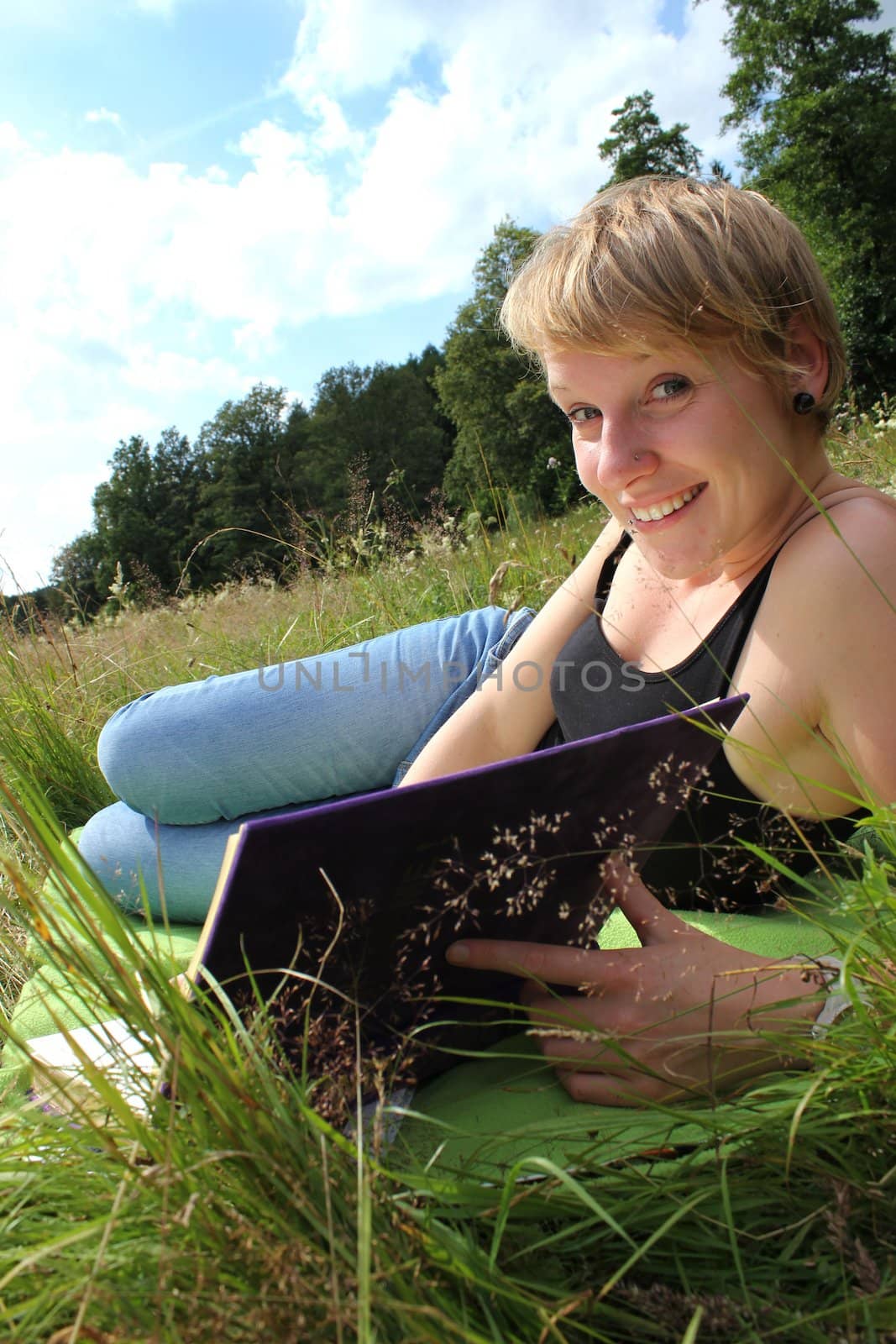 girl is reading a book on a summer meadow