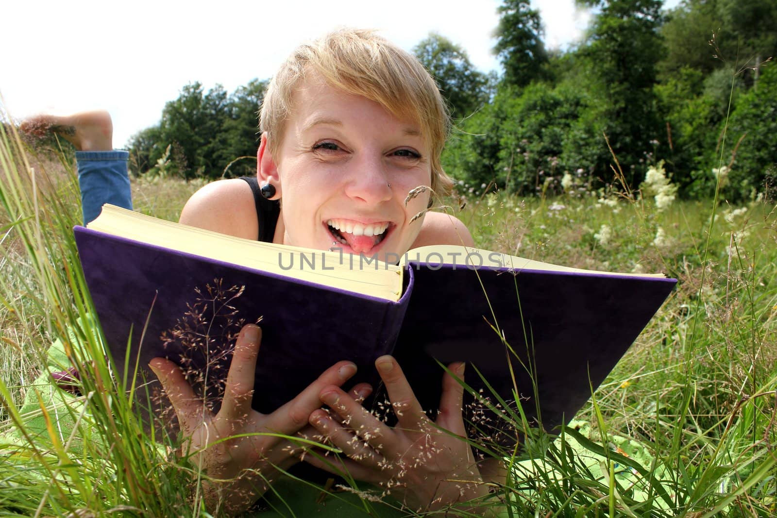 girl is reading a book on a summer meadow