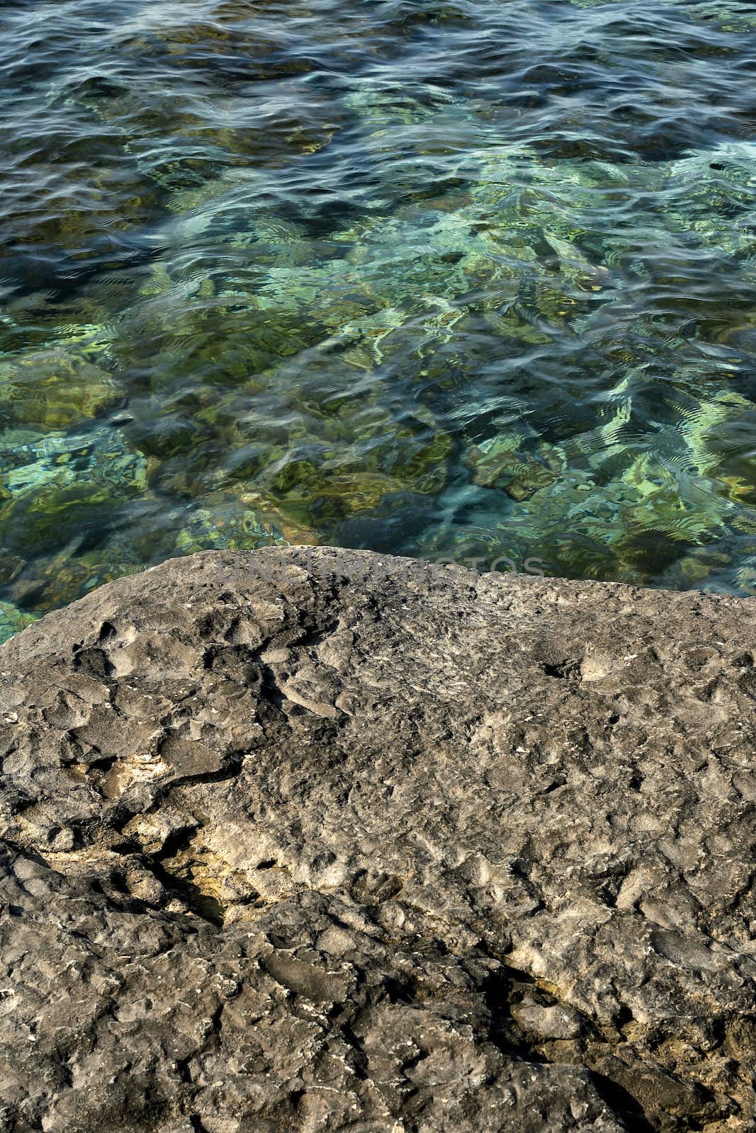 Background of a rough textured rock alongside cool pure fresh water in a rock pool