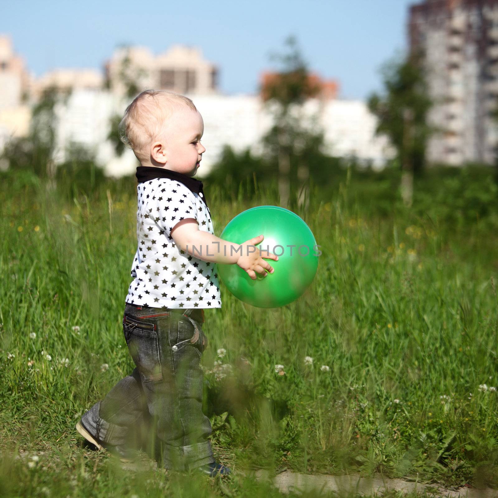  little boy play in green grass with green ball