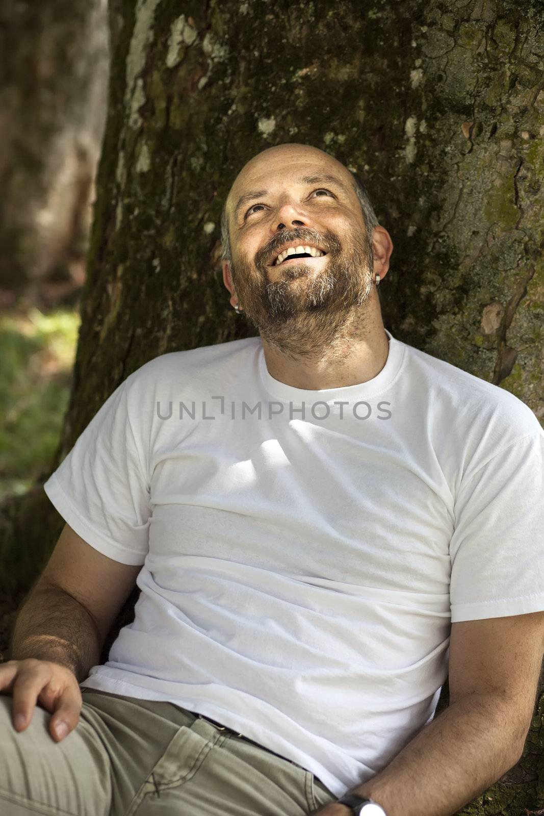 An image of a man with a beard relaxing under a tree
