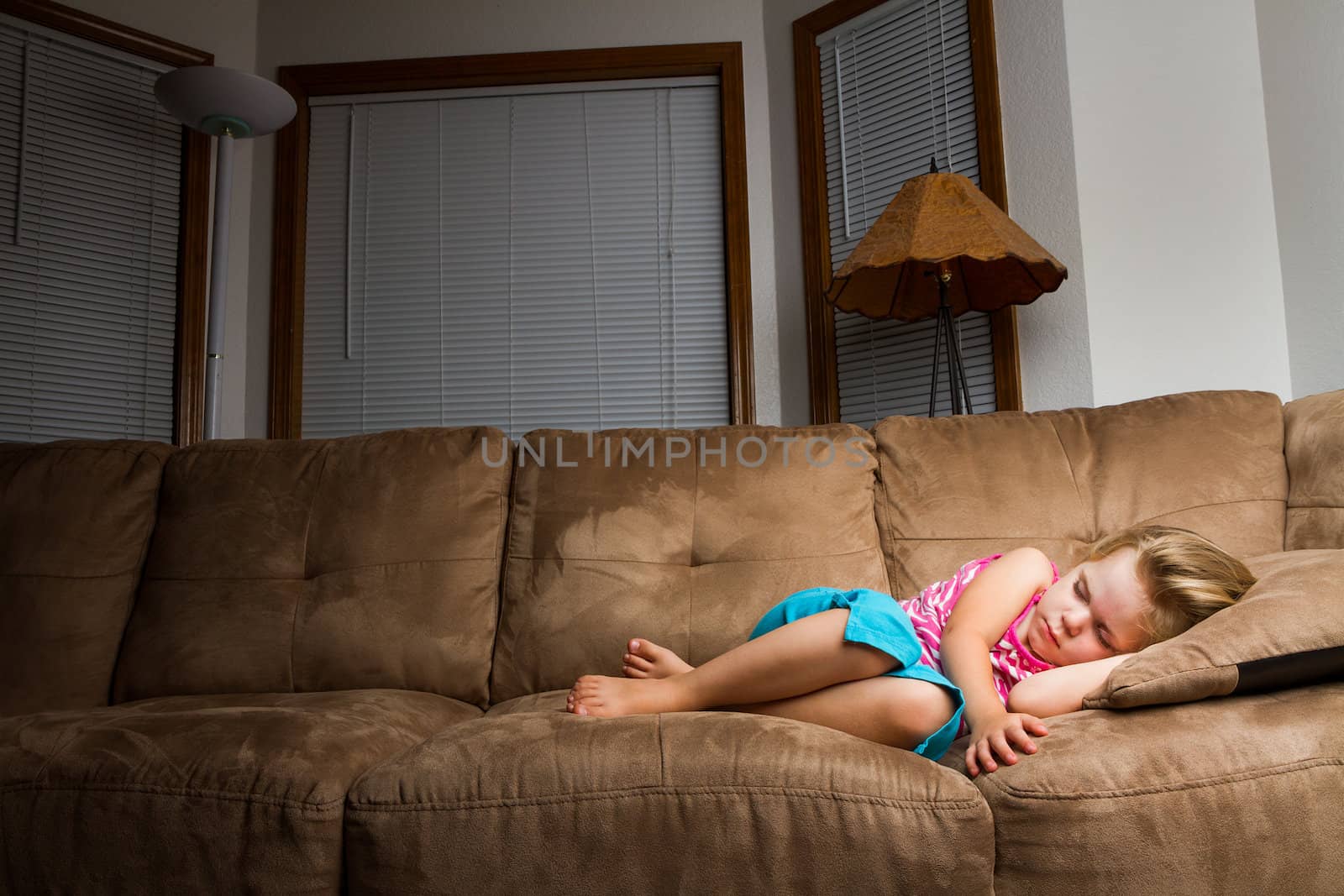 Child on couch curled up into a little ball. lighting focus on child falling off as it moves away