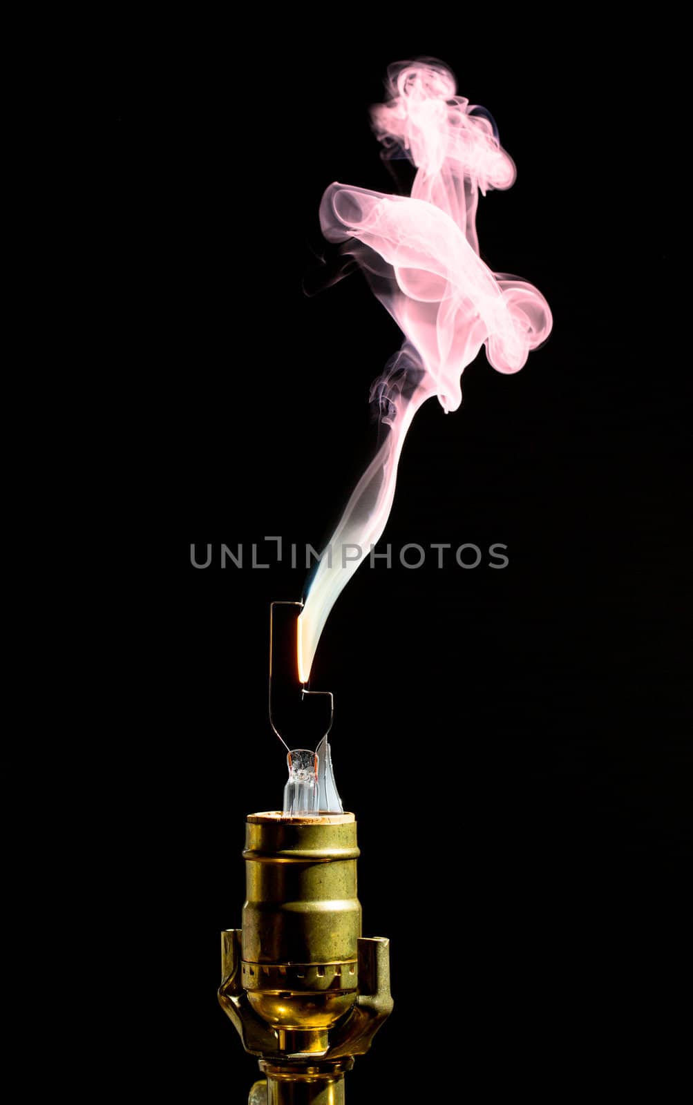 Filament on broken incandescent light bulb flares and gives off smoke