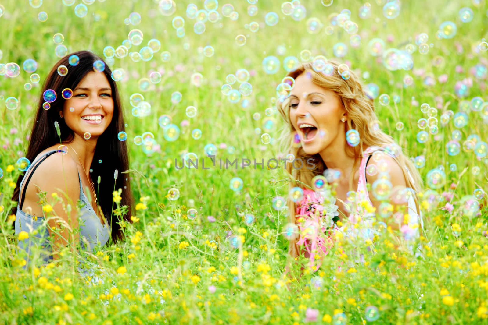 girlfriends on green grass field in soap bubbles