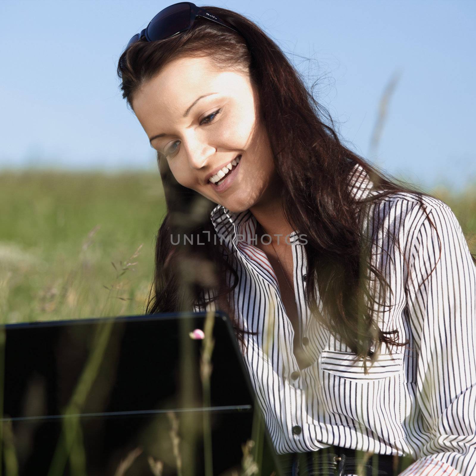 girl with laptop on green grass