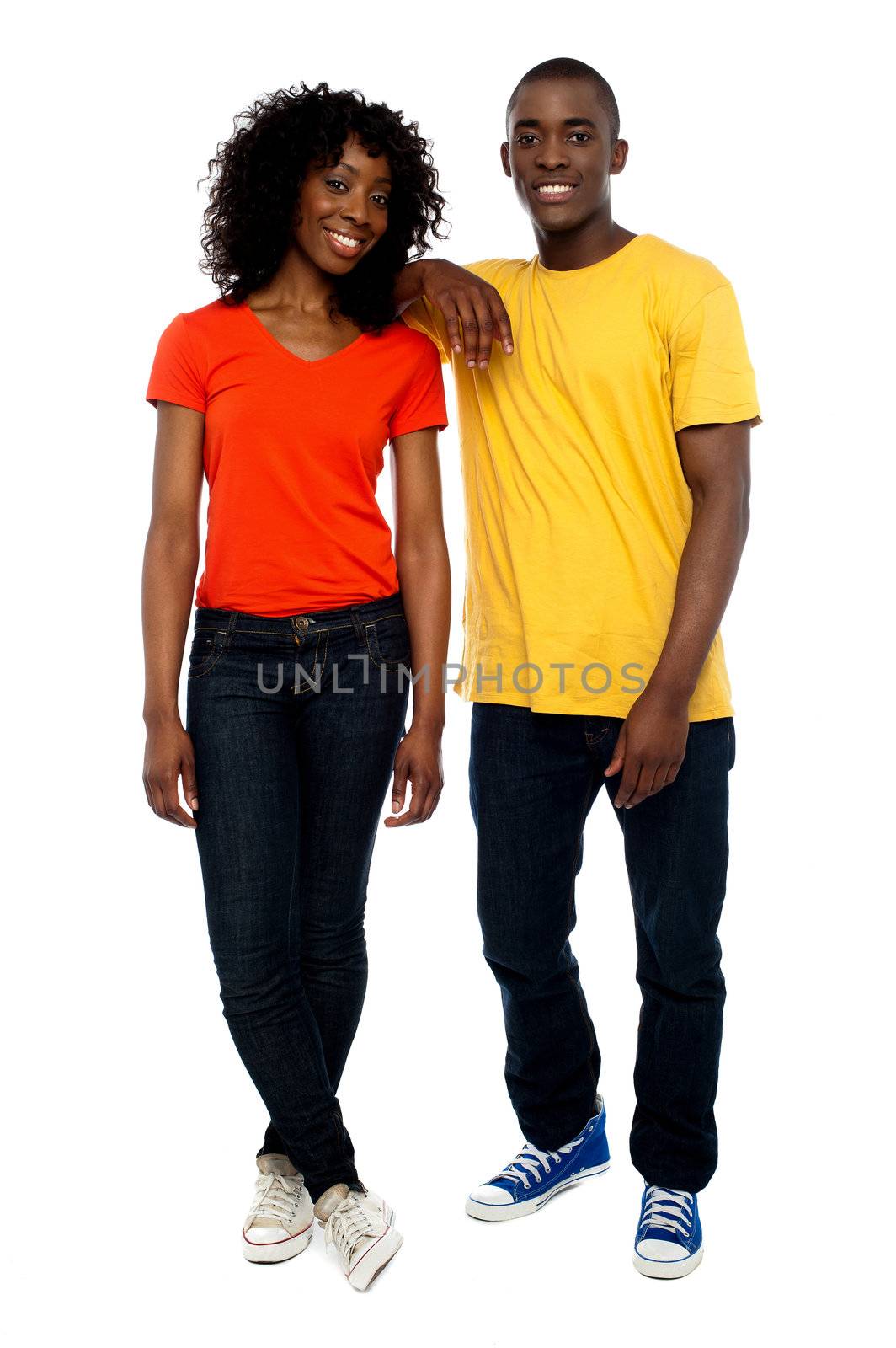 Two attractive african friends posing in style as guy rests his hands over his girlfriends shoulders