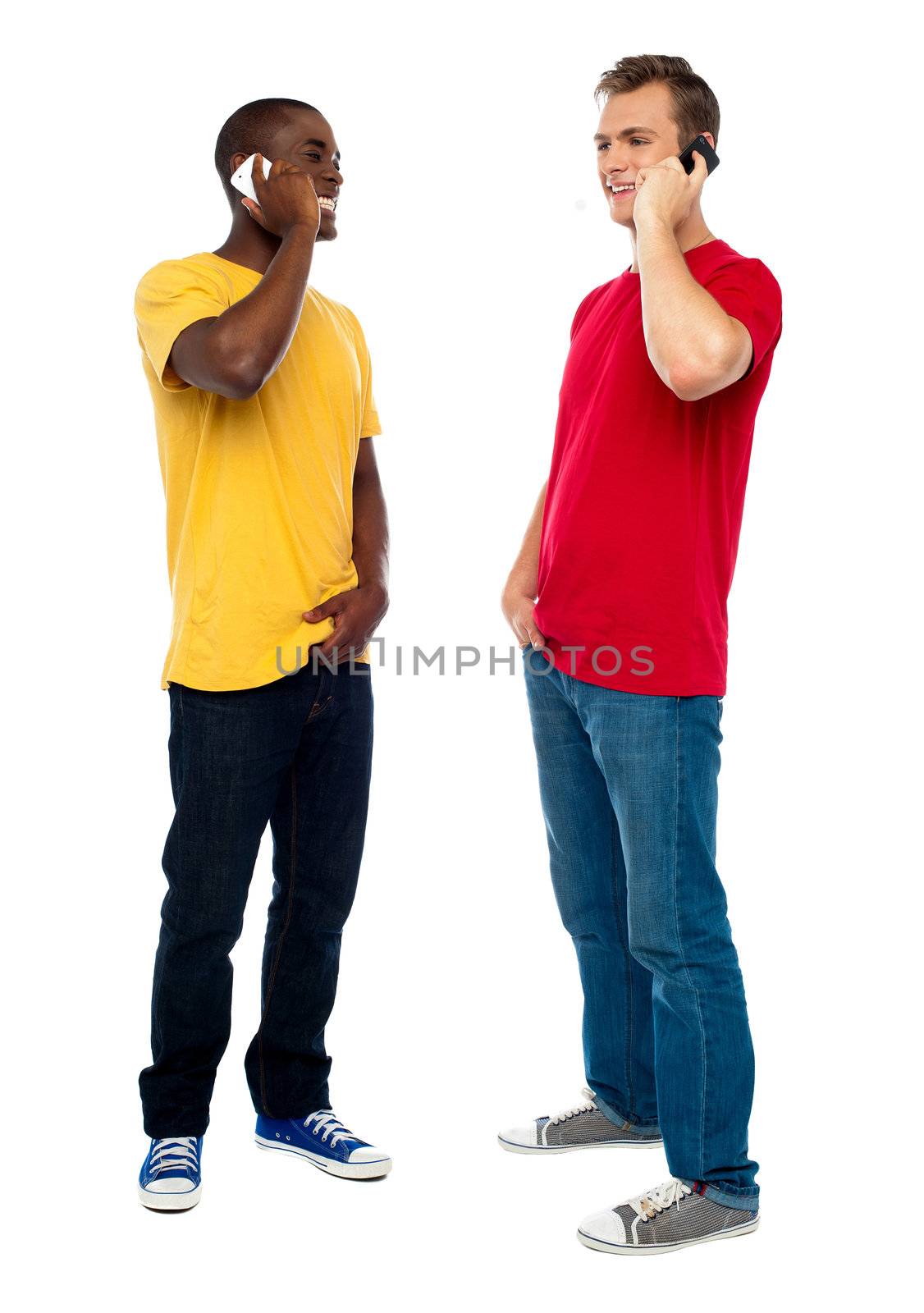 Trendy handsome guys attending call on cellphone by stockyimages