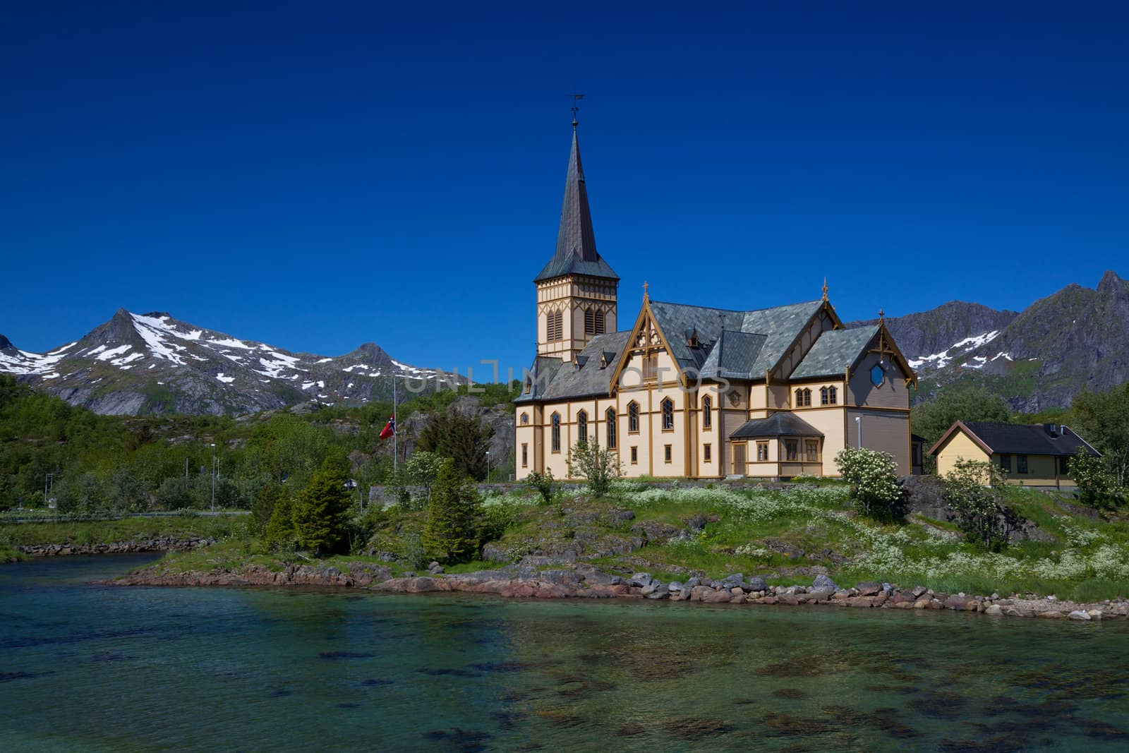 Picturesque Lofoten cathedral on Lofoten islands in Norway with snowy peaks in the background