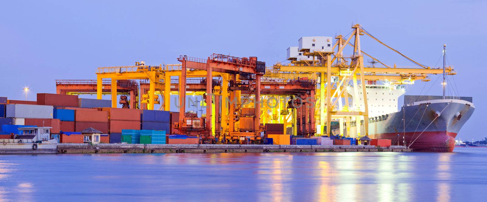 Panorama of Industrial Container Cargo freight ship with working crane bridge in shipyard at dusk for Logistic Import Export background