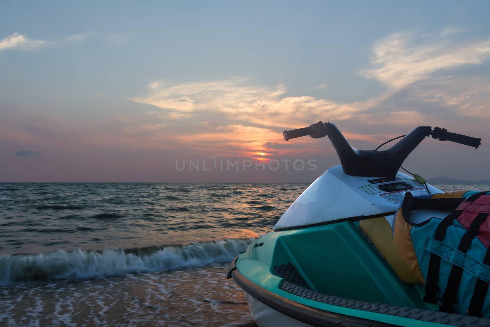 Jetski parked on a beach against blue sky and sunset