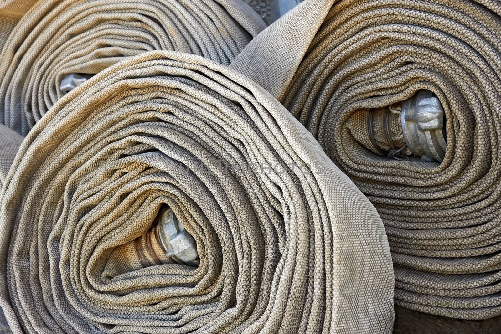 Several old rolled fire hoses with nozzles close-up