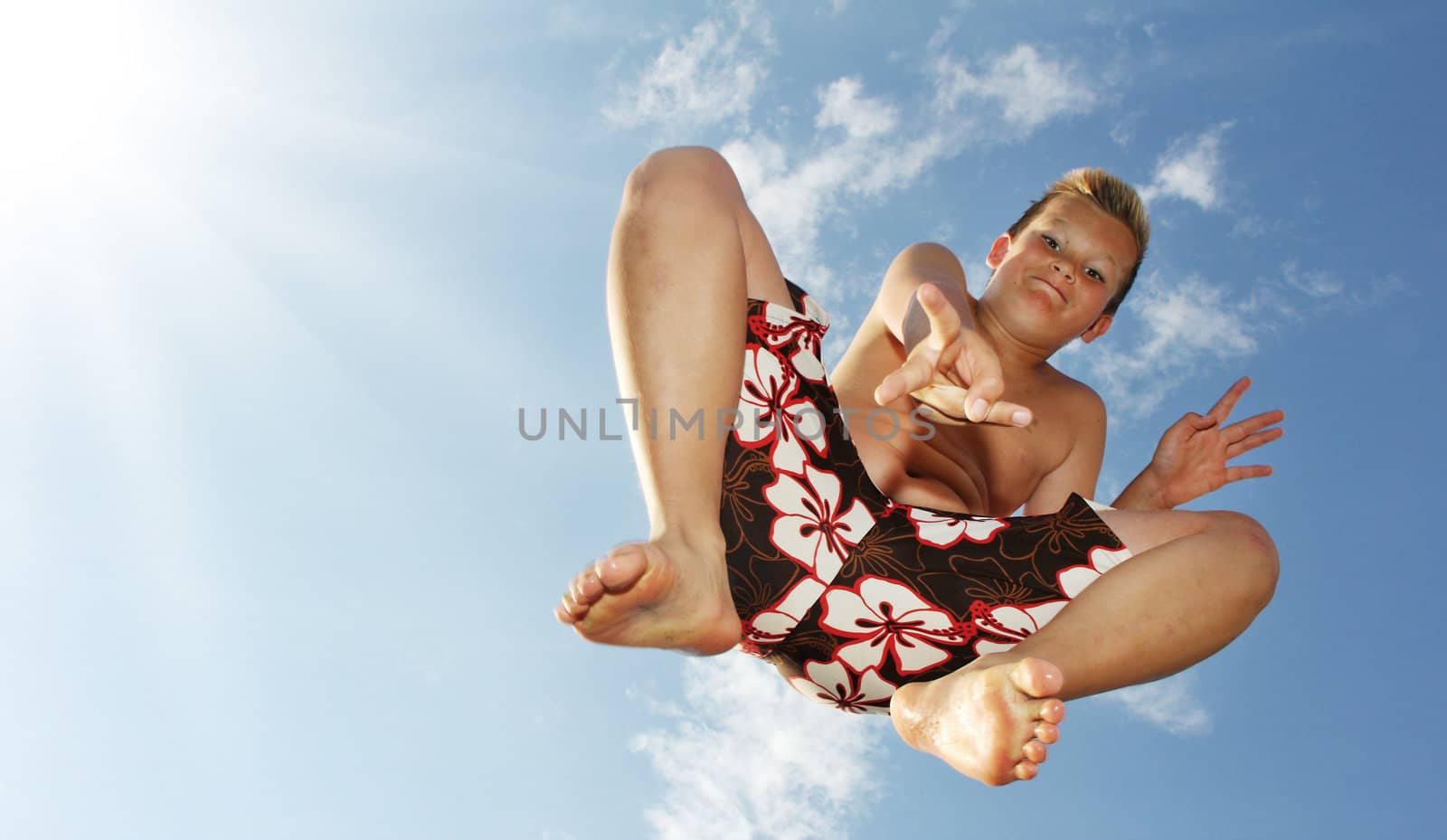 Little boy is jumping in front of the sky showing victory sign