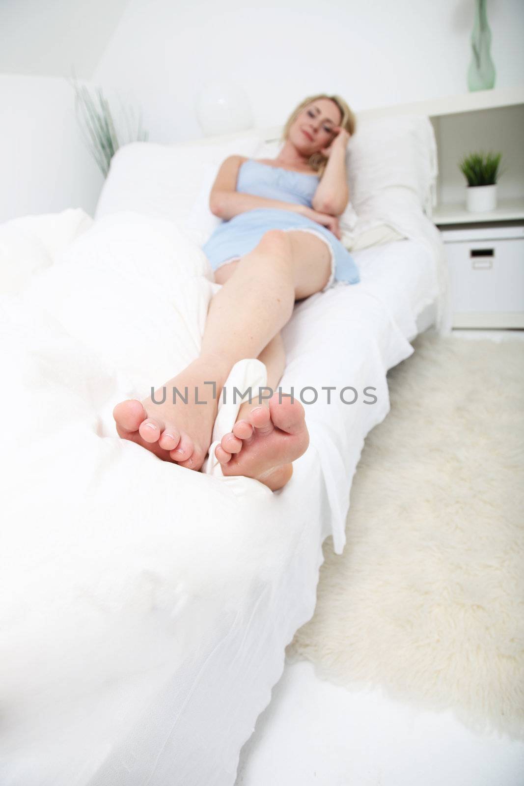 Toe to head view of a woman lying relaxing on her bed in her nightie with focus to the toes and feet 