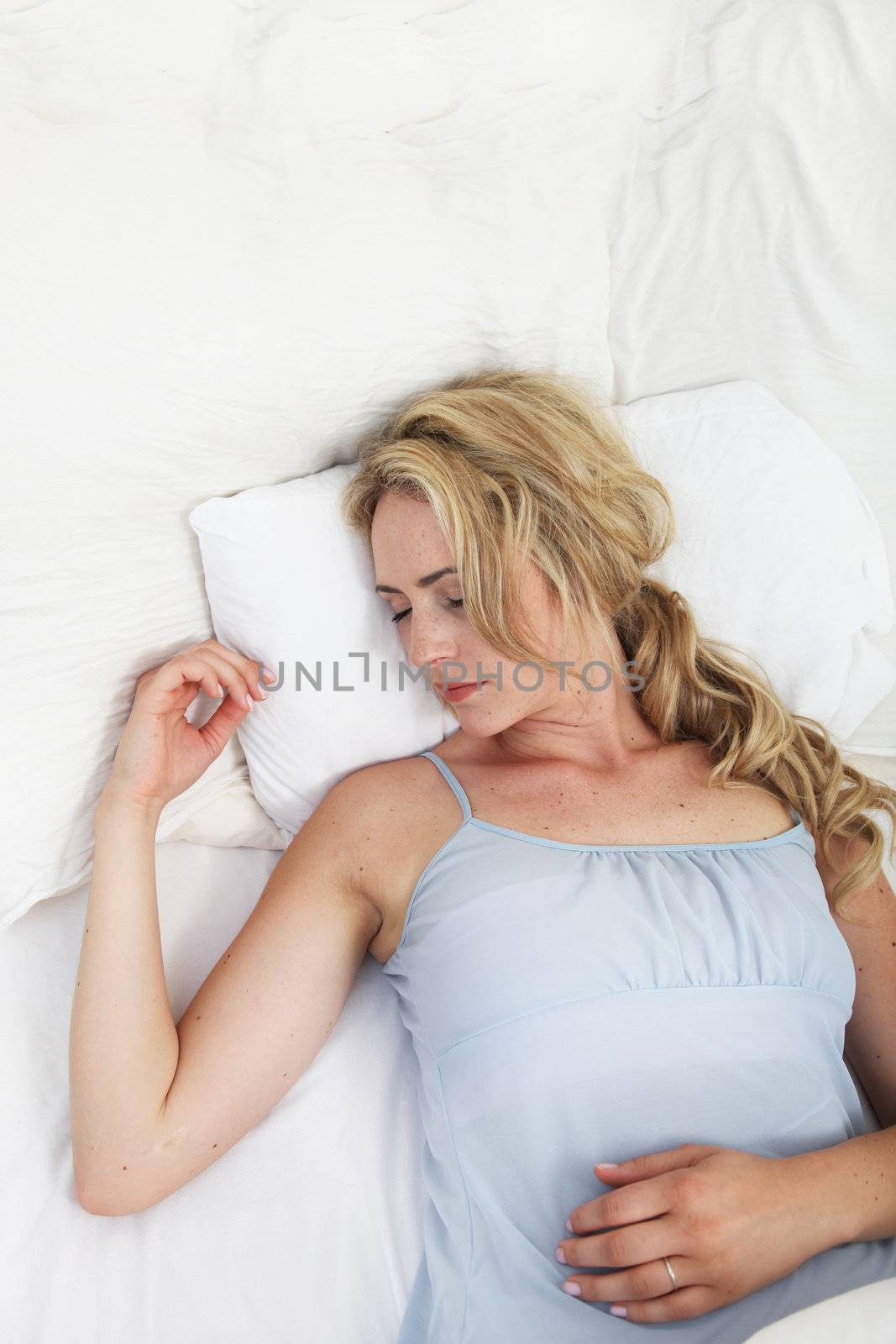 Overhead view of a sick woman lying on her back on her bed sleeping of the effects of her medication 