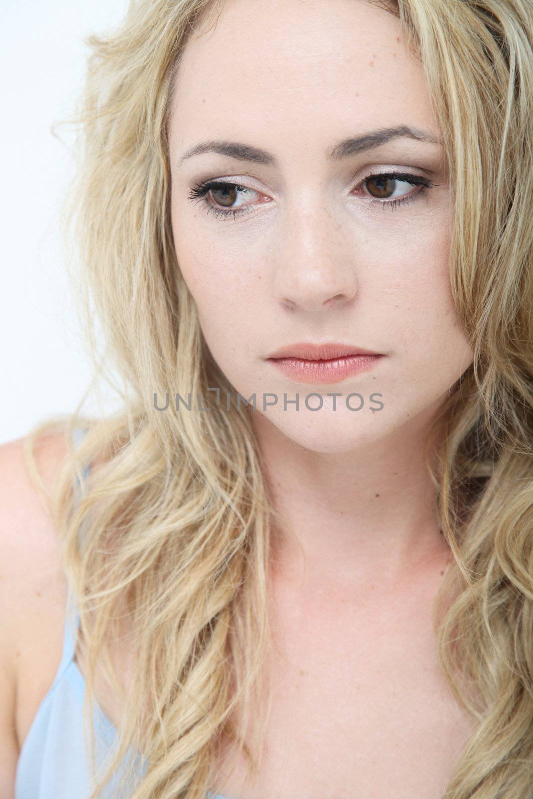 Beautiful sad young woman with a wistful expression lost in thought , closeup studio headshot on white 