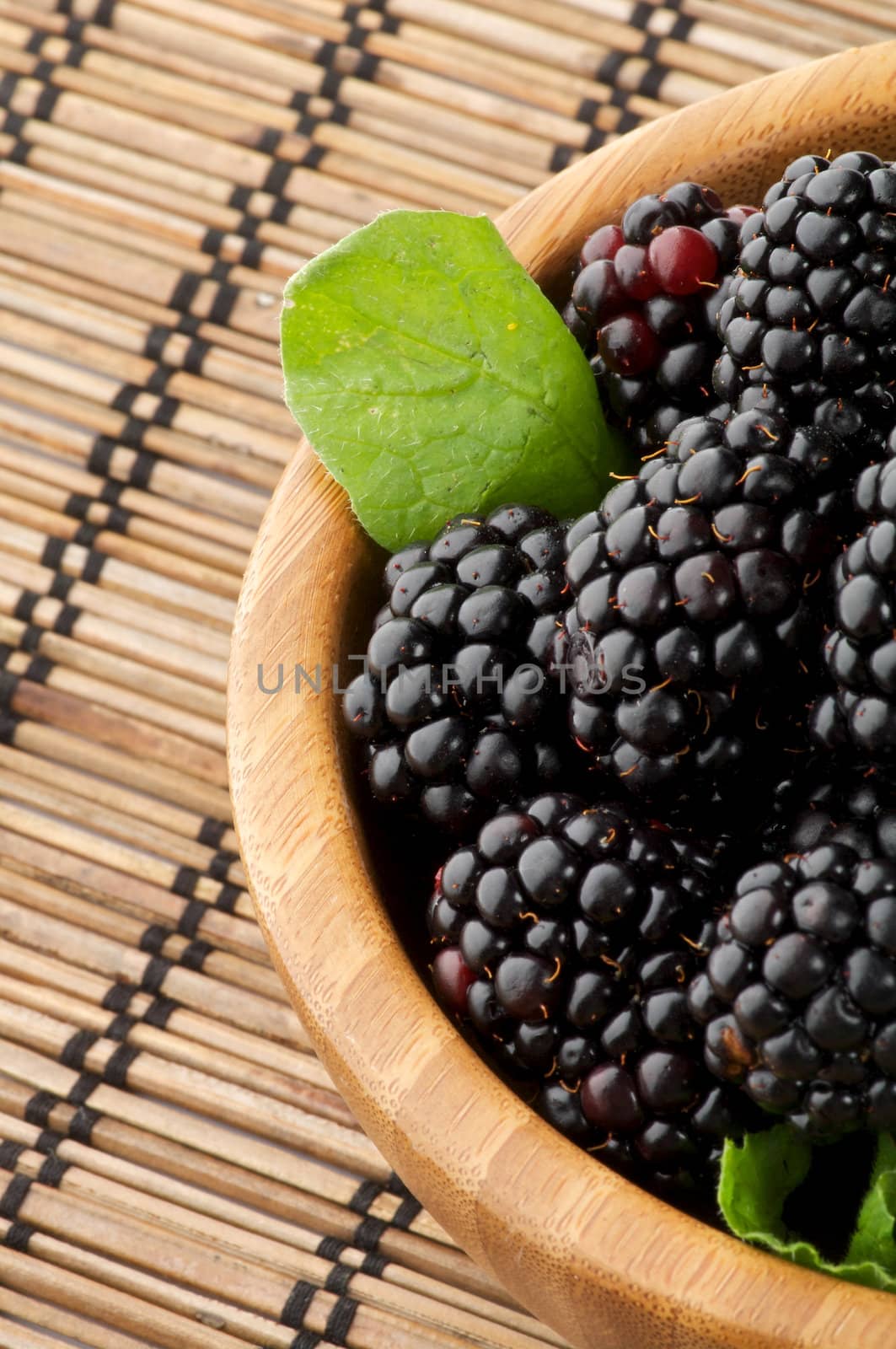 Perfect Blackberries in Wooden Bowl close up on Strawmat background