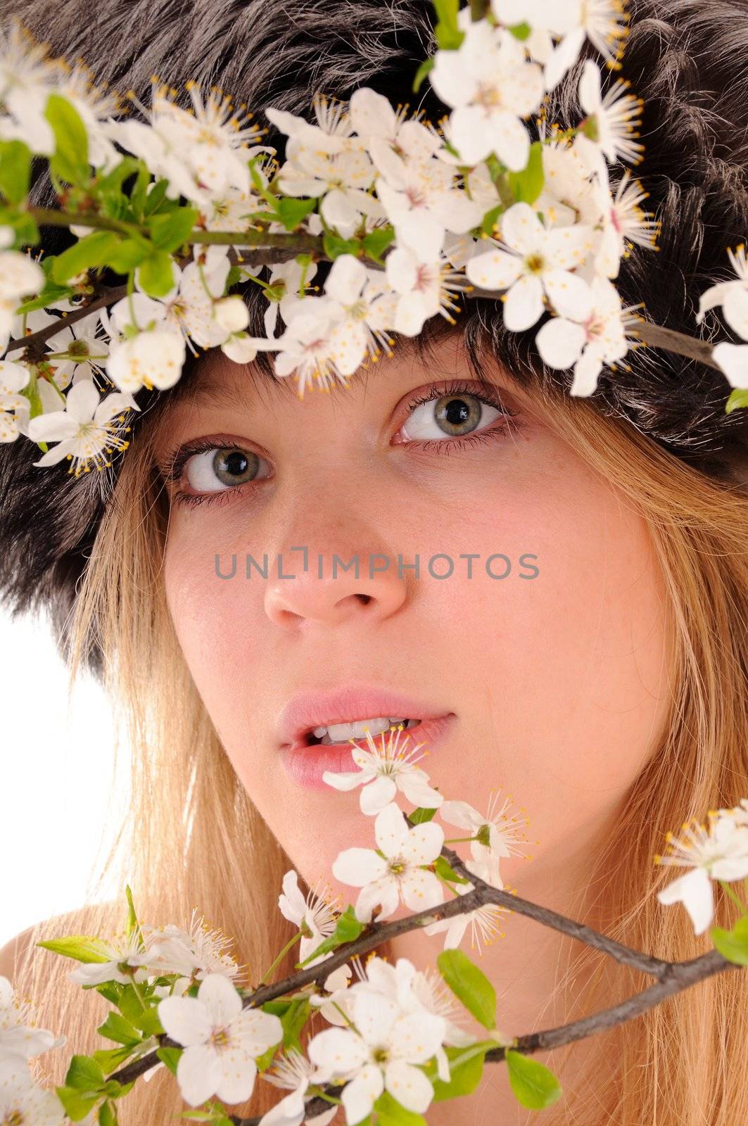 Winter beauty woman looks throught spring white cherry flowers. Focus on woman's eyes.