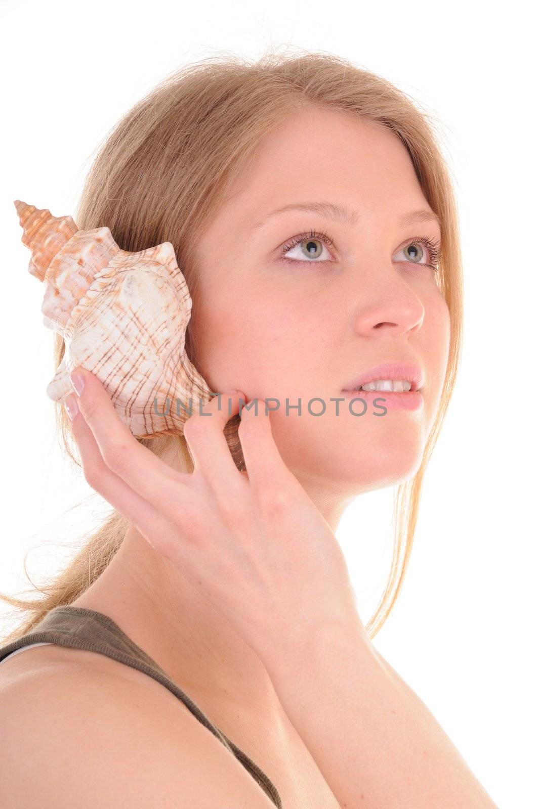 Young blonde woman is hearing waves in seashell