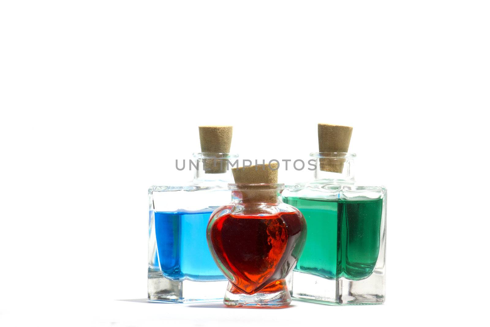 Clear glass vials filled with red, green and blue liquid on a white background