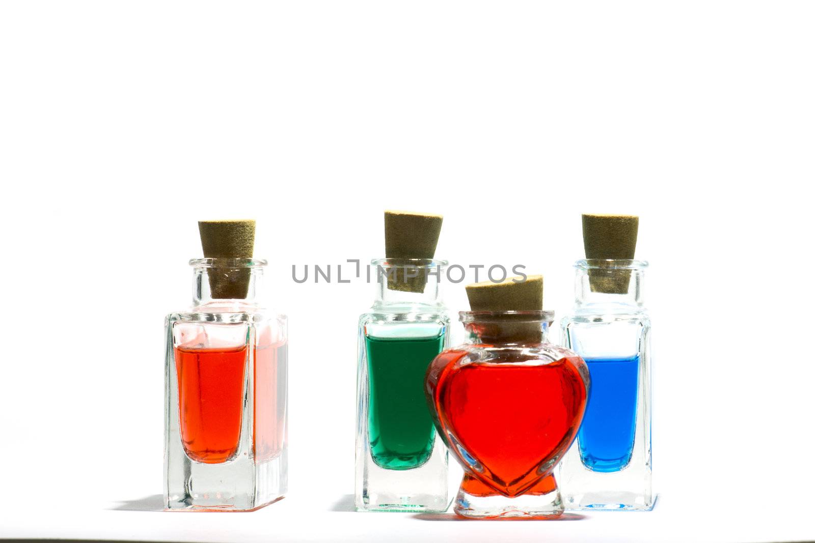 Clear glass vials filled with red, green and blue liquid on a white background