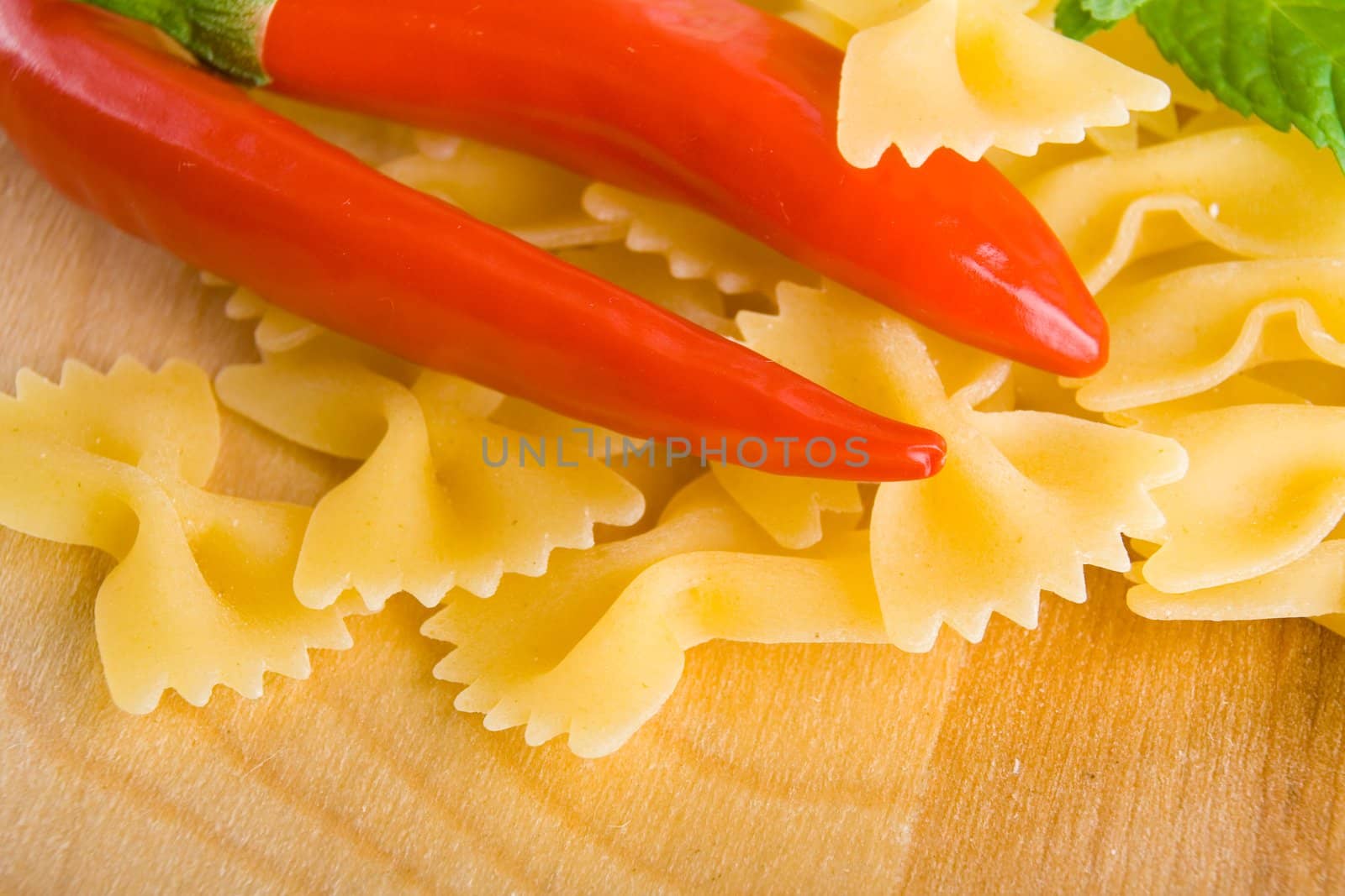 Golden raw dried Italian pasta with other ingredients on kitchen desk.