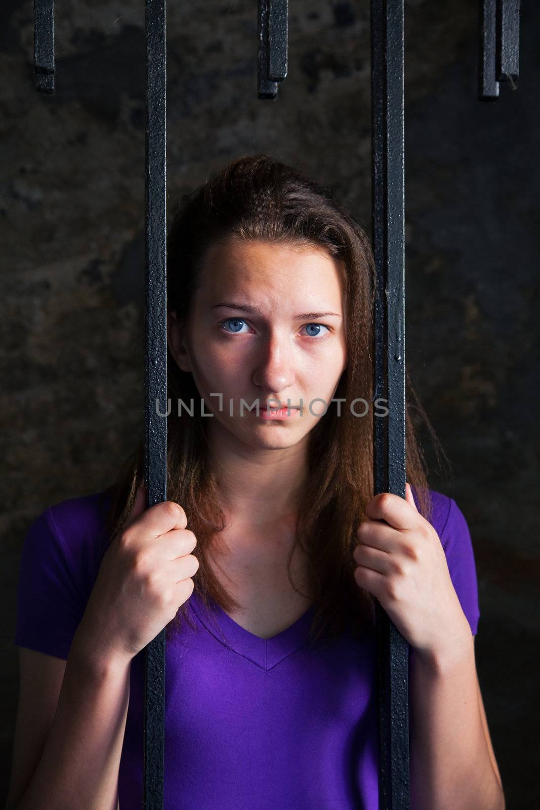 Young woman looking from behind the bars