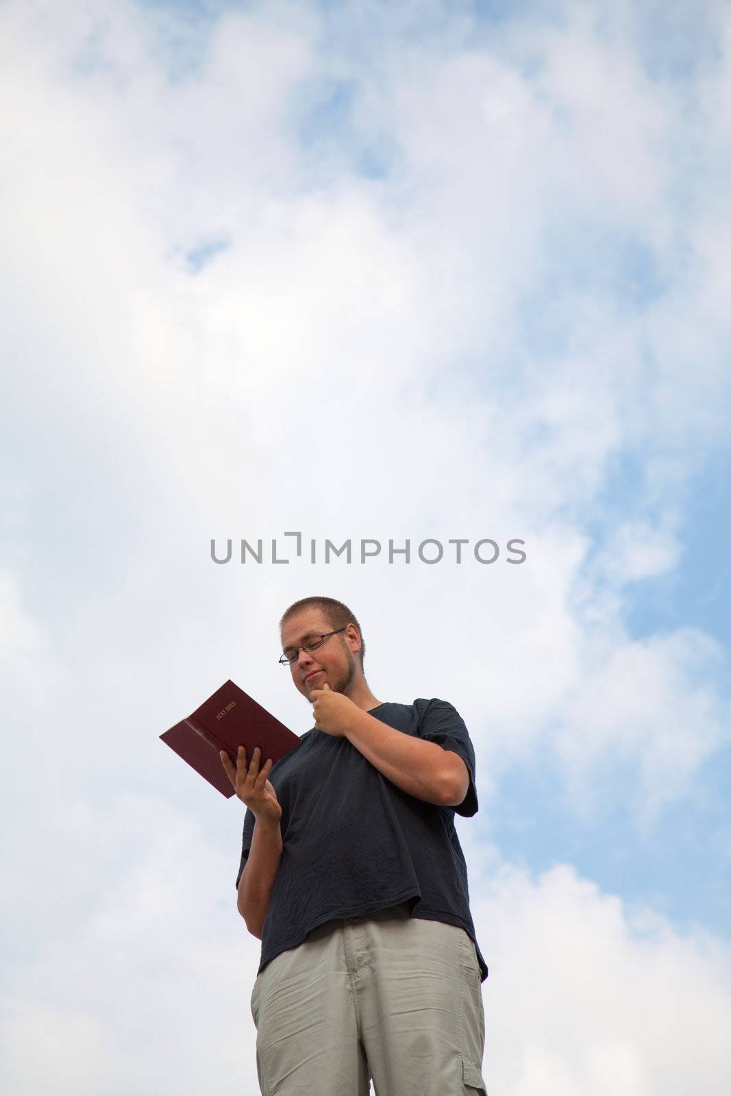 Young man staying with the Bible by AndreyKr
