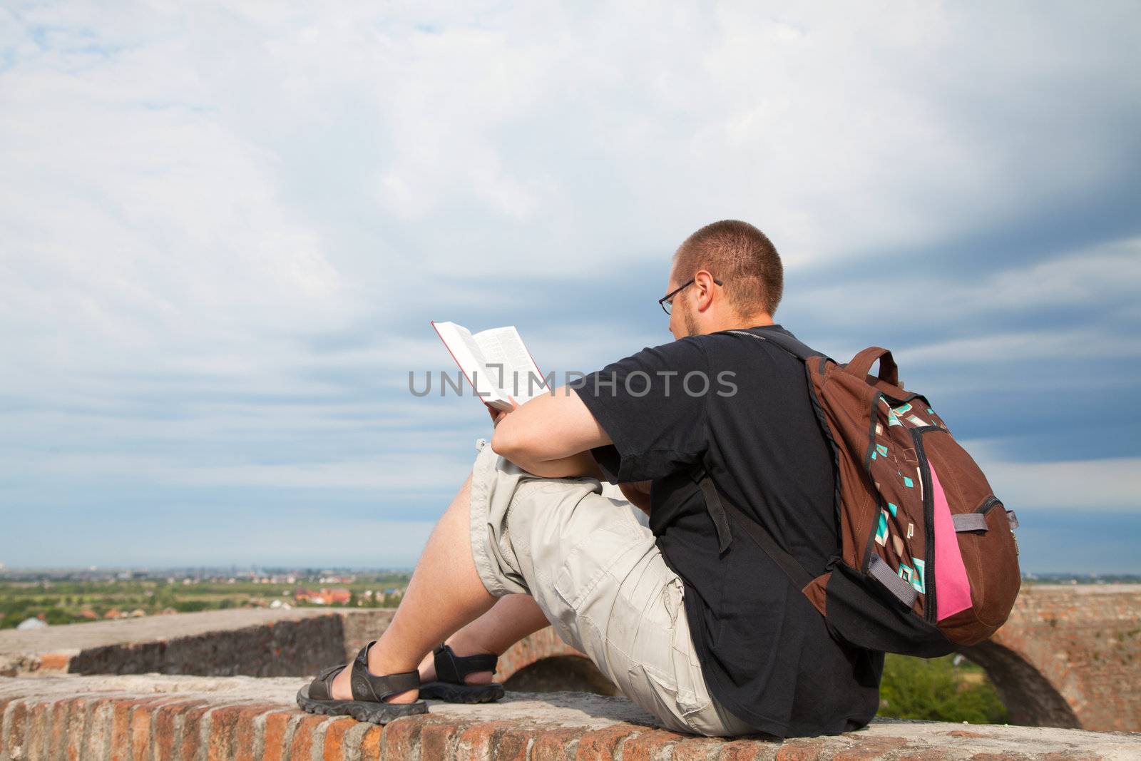 Young man sitting outdoors and meditating by AndreyKr