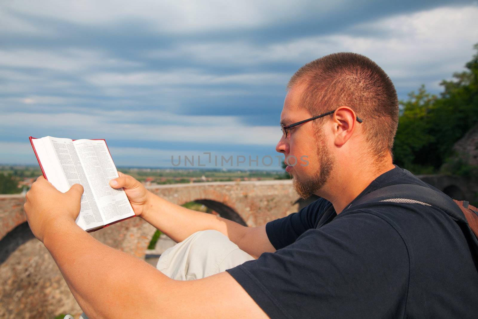 Young man reading the Bible sitting outdoors