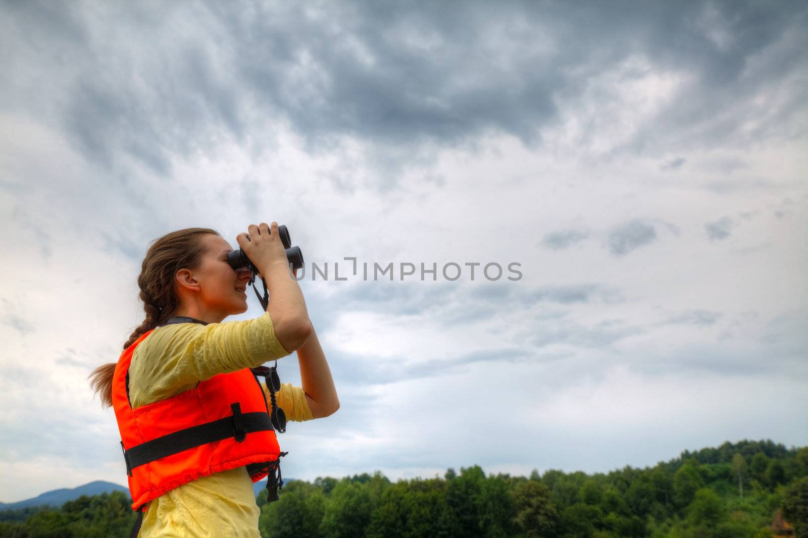Young woman looking to sky through binoculars