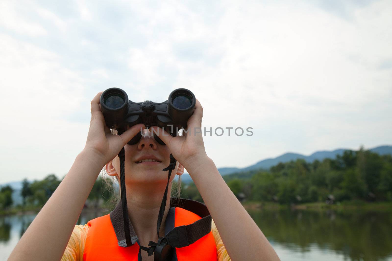 Young woman looking through binoculars by AndreyKr