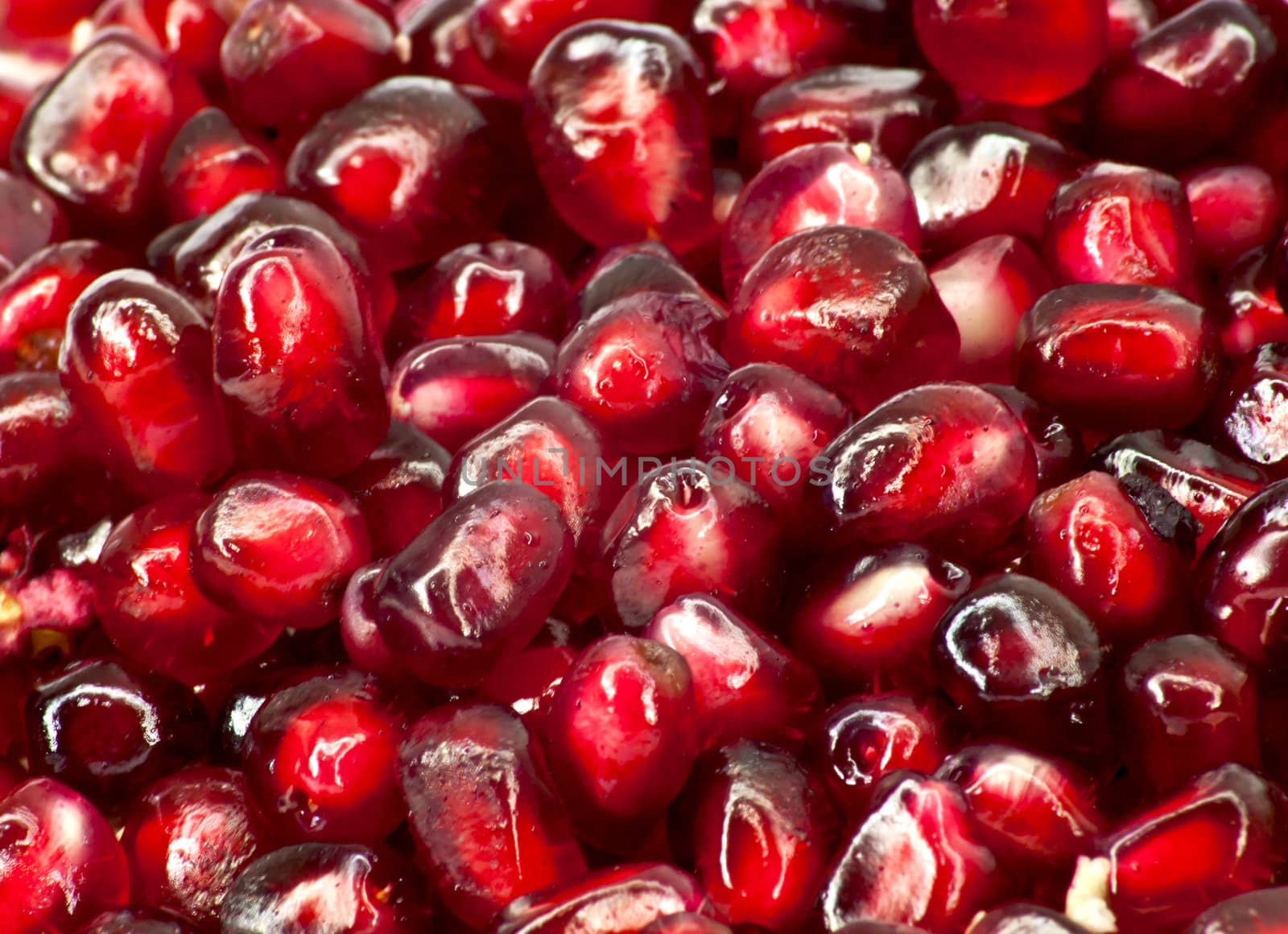 Extreme close up background of a red juicy ripe pomegranate fruit seeds 