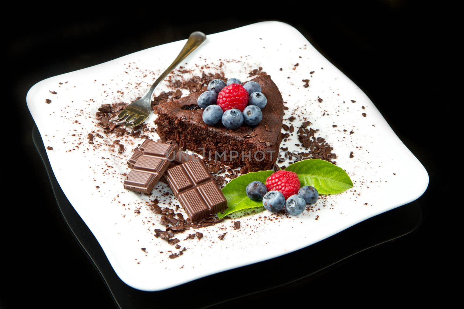 chocolate cake with fresh berry on white dish and black background