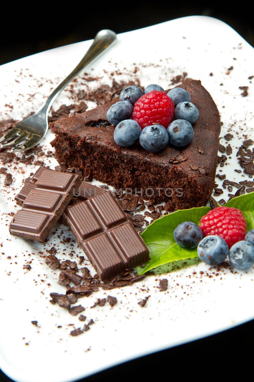 chocolate cake with fresh berry on white dish and black background