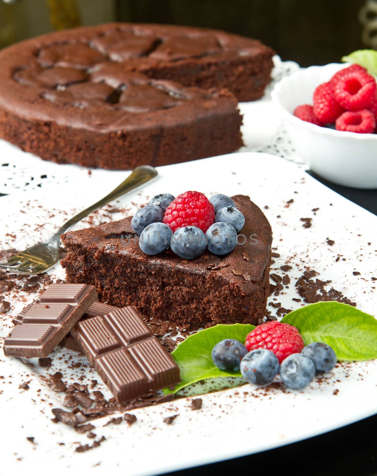 chocolate cake with fresh berry on white dish and black background