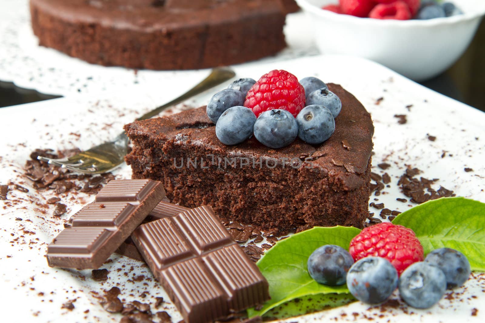 chocolate cake with fresh berry on white dish and black background