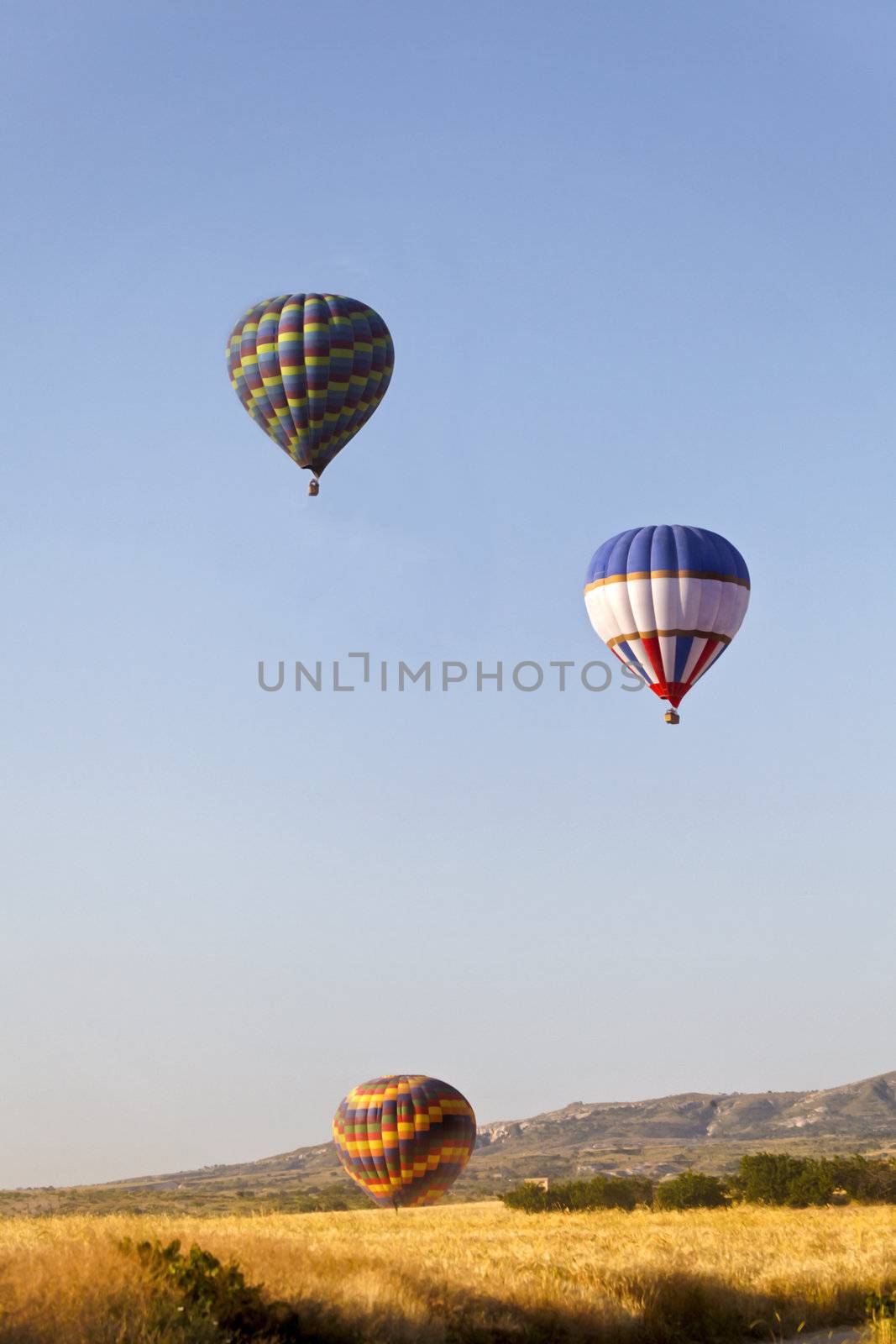 Colourful hot air balloons rising over the ridge. A generic portrait was taken early morning in Cappadocia, Turkey.