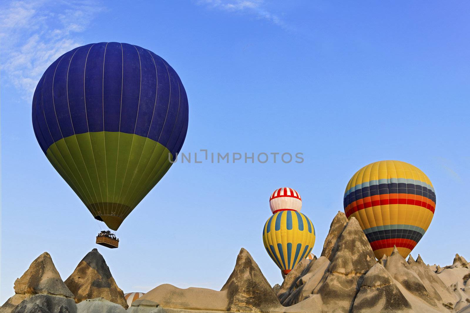 Hot air balloons captured coming over the limestone ridge near Goreme, Caapadocia, Turkey. The weathered mineral peaks which have eroded through evolution present a surreal backdrop to the striking colours of the passenger ladened aircraft.