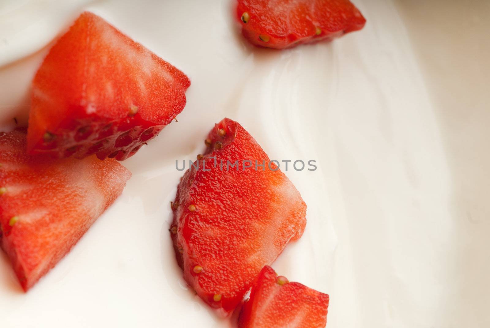 Juicy red strawberry pieces floating in cream