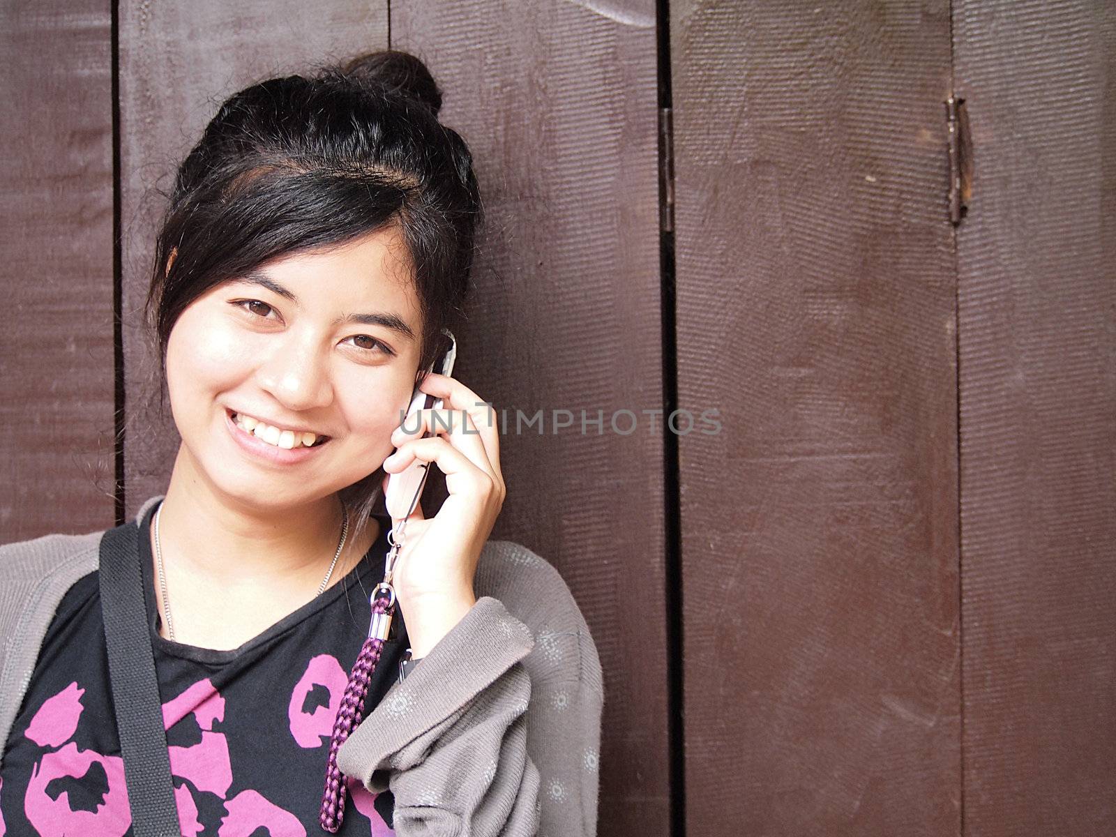 happy smiling teenage girl with the mobile phone  on wood background.      