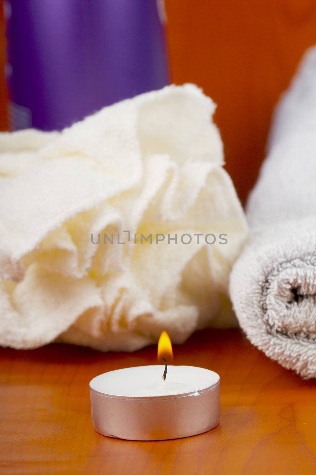 Candle, towels and other bath stuff over wooden background