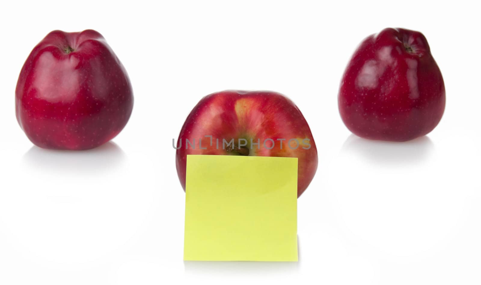 Three red apples with yellow stiker note isolated on white background. Shallow depth of fileld.