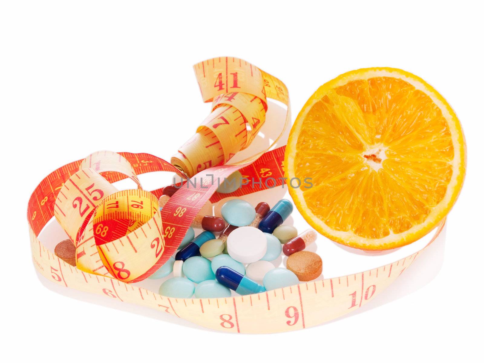 Concept of diet and medicine.  Heap of pills, orange slice and measuring tape with reflection on white background. Focus on orange.