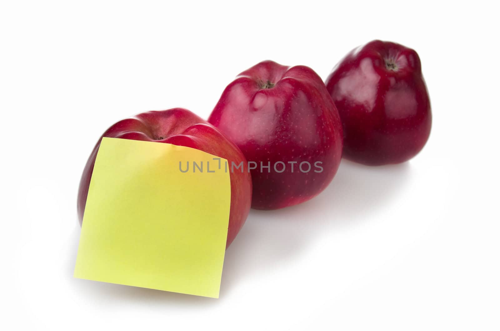 Three red apples with yellow stiker note isolated on white background.  Shallow depth of field.