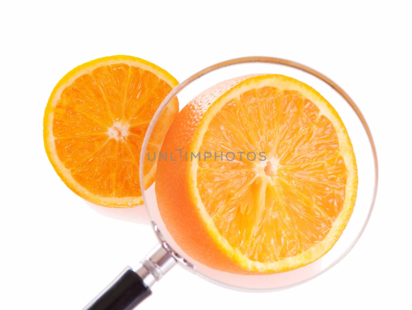 Juicy orange slice through magnifying glass. Shallow depth of fields, focus on orance in loupe.