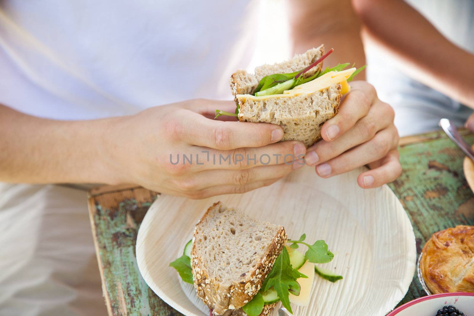 Closeup of male hands holding a healthy sandwich with cheese and lettuce